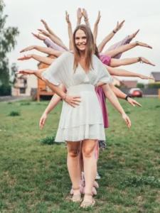 Kobieta pozująca z przyjaciółkami tworzącymi efekt wachlarza z rąk podczas wieczoru panieńskiego