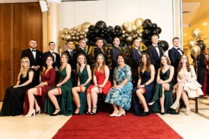 Studniówka 2023 Toruń – pamiątkowe zdjęcie klasowe z wychowawcą na tle dekoracji balowej