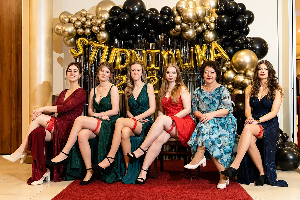 Studniówka 2023 Toruń – uczennice z wychowawczynią podczas pamiątkowej sesji na tle dekoracji balowej